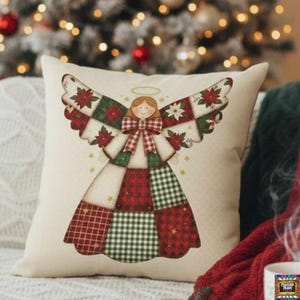 Puede incluir: Cojín decorativo cuadrado de color crema con un diseño de ángel. El ángel tiene alas y vestido de patchwork con patrones rojos, verdes y blancos, un halo dorado y un lazo. El cojín está sobre un sofá, con un árbol de Navidad al fondo.