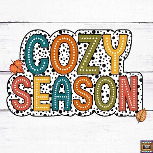 Könnte beinhalten: Ein farbenfrohes Grafikdesign mit weißem Hintergrund und schwarzen Punkten. Der Text "Cozy Season" ist in einer Retro-Schriftart gehalten, wobei jeder Buchstabe eine andere Farbe hat.