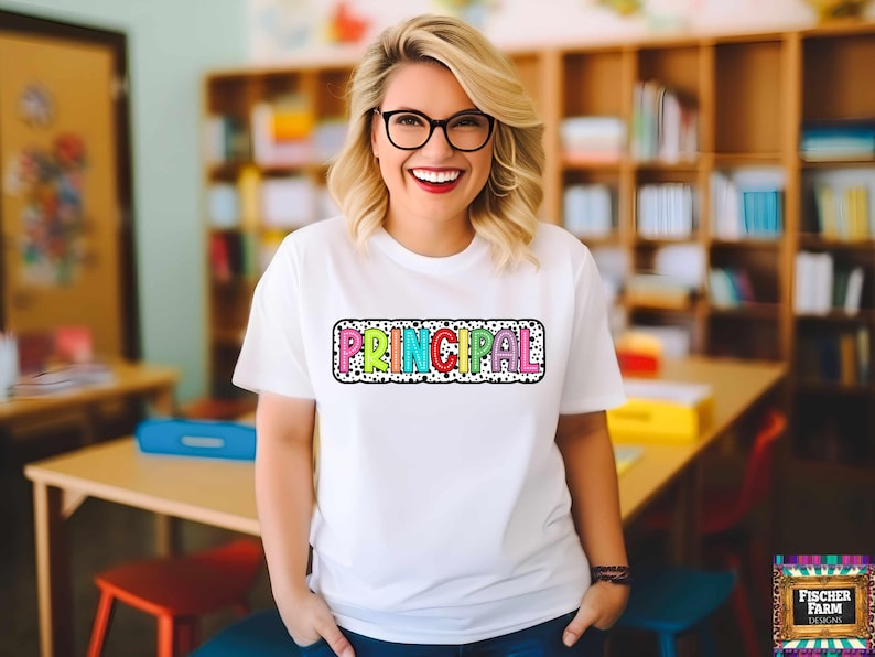 May include: A white t-shirt with a colorful "PRINCIPAL" graphic on the front. The graphic is surrounded by black polka dots and has a black outline.