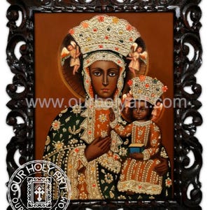 Puede incluir: Icono de la Virgen María y el Niño, enmarcado en madera oscura. Las figuras están representadas con tonos de piel oscuros, usando coronas y túnicas ornamentadas. La obra de arte presenta adornos dorados y con forma de joya, con ángeles en el fondo. El marco tiene un diseño tallado intrincado.