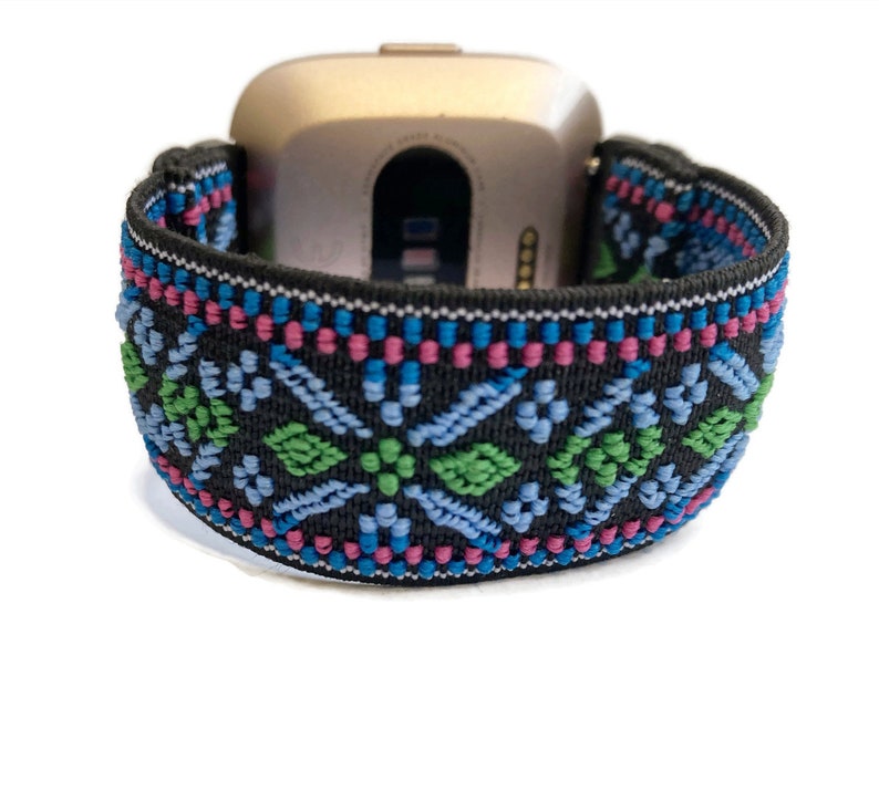 May include: A black watch band with a colorful geometric pattern. The band is made of elastic material and has a woven design with blue, green, pink, and white accents.