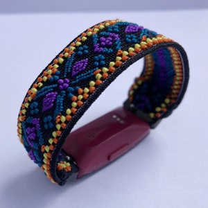 May include: A black fitness tracker with a colorful patterned band. The band has a geometric design with orange, yellow, blue, and purple accents.