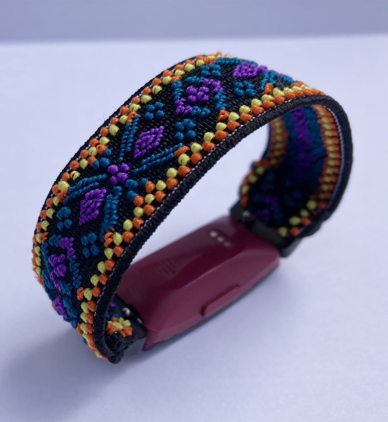 May include: A black fitness tracker with a colorful patterned band. The band has a geometric design with orange, yellow, blue, and purple accents.