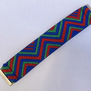 May include: A blue, red, and green zig-zag patterned elastic band with gold metal ends.