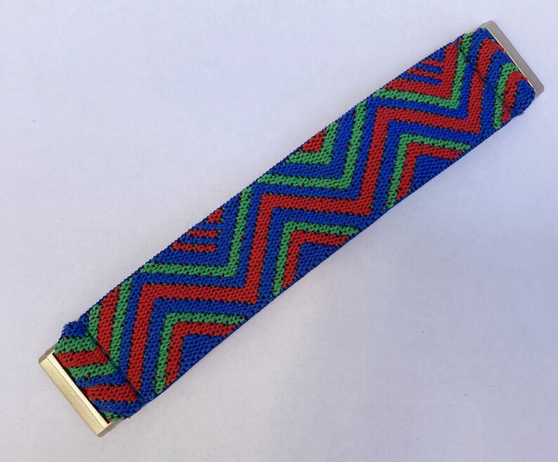 May include: A blue, red, and green zig-zag patterned elastic band with gold metal ends.