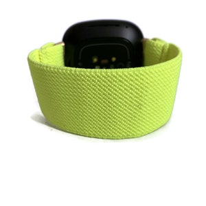 Op de afbeelding: Een felgeel fitness tracker bandje met een zwart horloge gezicht.