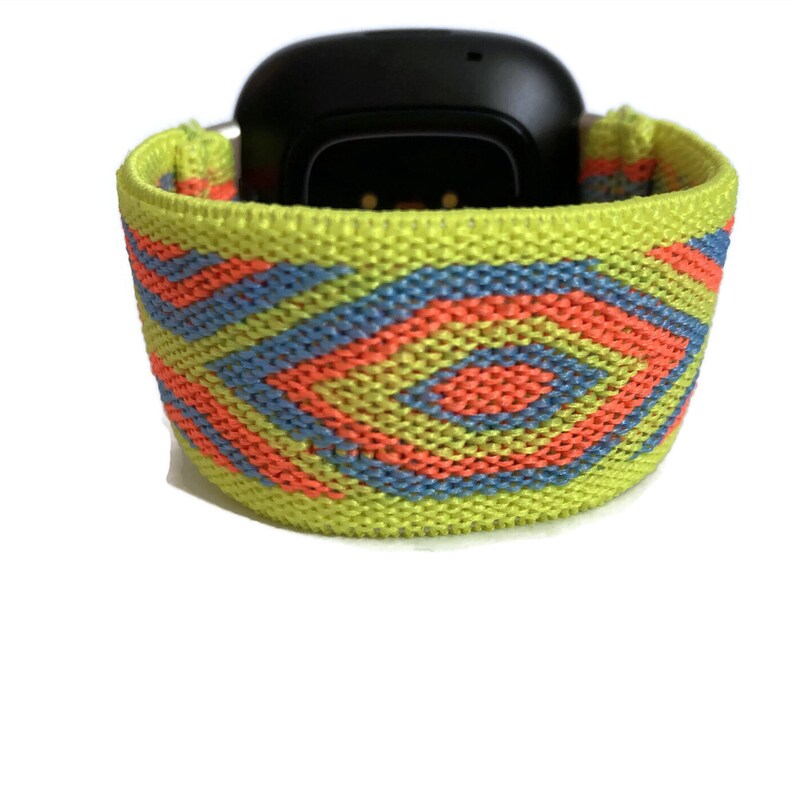 May include: A bright yellow, blue, and orange patterned elastic watch band. The band is made of woven fabric and has a geometric design.