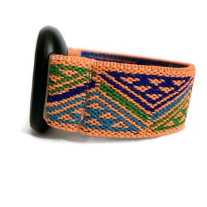 May include: A woven watch band with a geometric pattern in shades of orange, blue, and green. The band is made of a soft, stretchy material and has a black buckle.