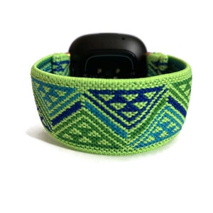 May include: A green and blue patterned woven watch band with a geometric design.
