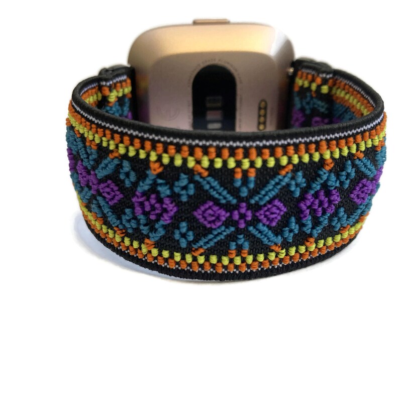 K&ouml;nnte beinhalten: Ein schwarzes elastisches Armband mit einem farbenfrohen geometrischen Muster in Orange-, Gelb-, T&uuml;rkis- und Violettt&ouml;nen. Das Armband ist f&uuml;r eine Smartwatch konzipiert.