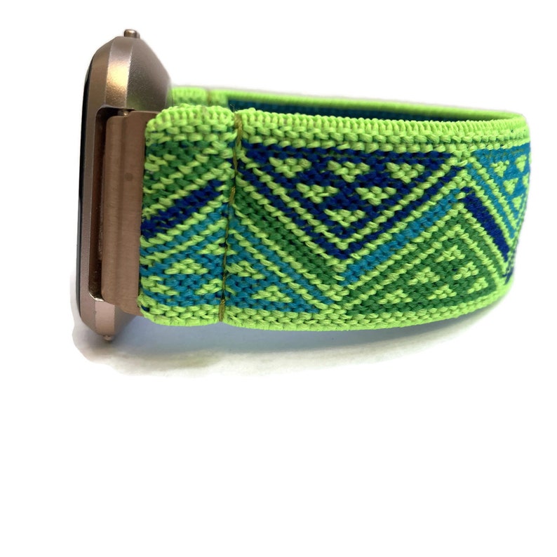 May include: A green and blue patterned elastic watch strap. The strap is made of a soft, stretchy material and has a geometric design.