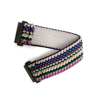 May include: A colorful woven belt with a black buckle. The belt is made of a variety of colors, including pink, blue, green, and yellow.