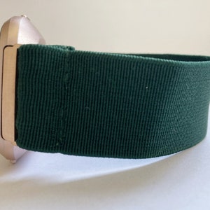Op de afbeelding: Een smartwatch van ros&eacute;goud met een donkergroene stoffen band.