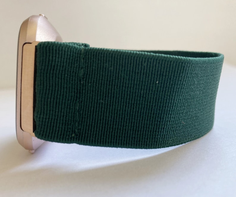 Op de afbeelding: Een smartwatch van ros&eacute;goud met een donkergroene stoffen band.