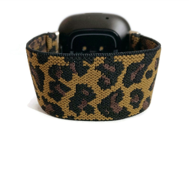 May include: A black fitness tracker with a brown and black leopard print elastic band.