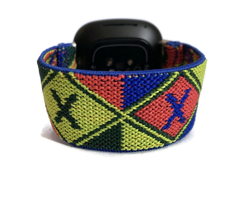 May include: A colorful woven watch band with a blue, red, green, and yellow geometric pattern. The band features a black and white logo.