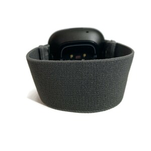 Pode incluir: Um rastreador de fitness preto com uma banda el&aacute;stica cinza. O rastreador tem uma pequena tela e um sensor de frequ&ecirc;ncia card&iacute;aca.