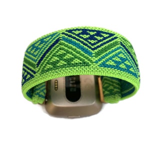 May include: A green, blue and black patterned watch band with a geometric design. The band is made of a soft, stretchy material.