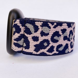 May include: A navy blue and pink leopard print elastic watch band.