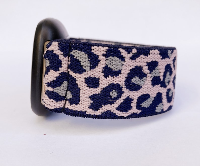 May include: A navy blue and pink leopard print elastic watch band.