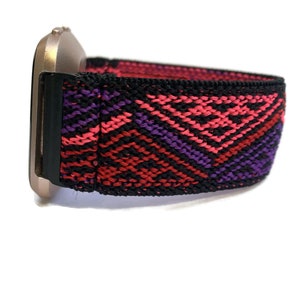 Puede incluir: Una banda el&aacute;stica para reloj con estampado negro, rojo y morado. La banda est&aacute; hecha de una tela tejida con un dise&ntilde;o geom&eacute;trico.