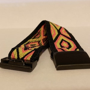 Op de afbeelding: Een elastisch horlogebandje in zwart en geel met een patroon en een zwarte gesp.