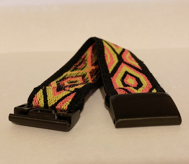 Op de afbeelding: Een elastisch horlogebandje in zwart en geel met een patroon en een zwarte gesp.