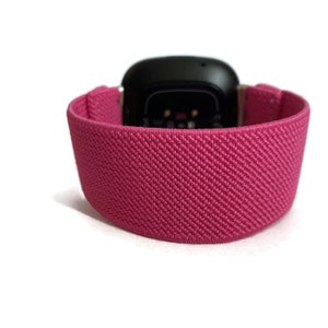 May include: A pink sport band for a smartwatch. The band is made of a soft, stretchy material and has a textured surface.