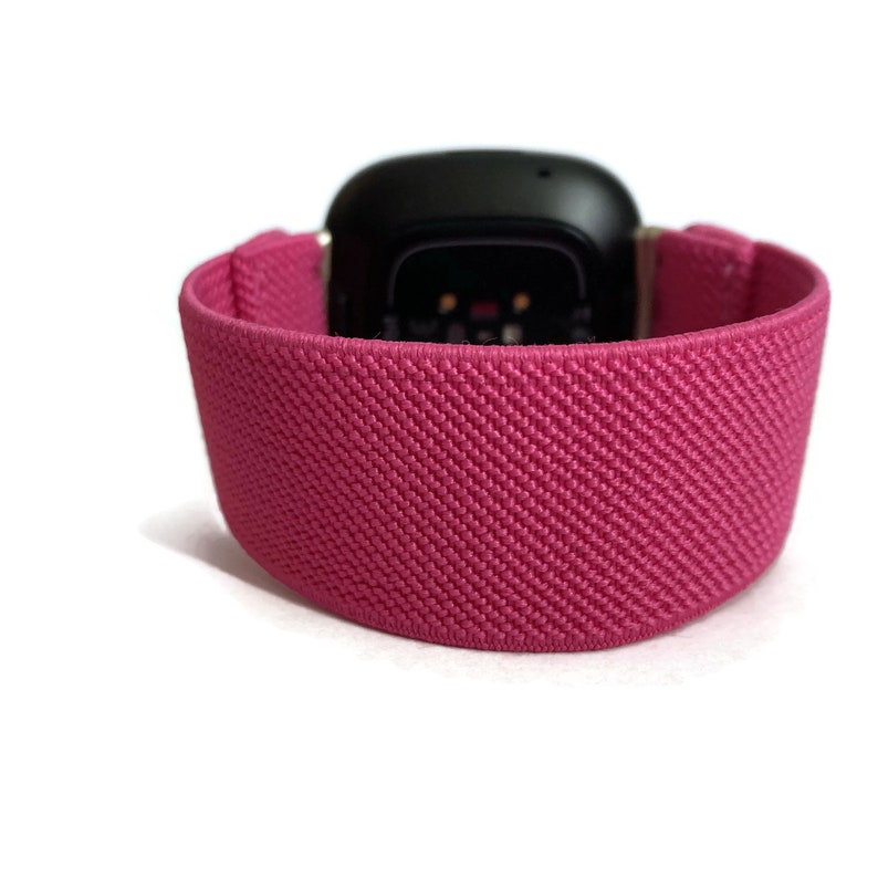 May include: A pink sport band for a smartwatch. The band is made of a soft, stretchy material and has a textured surface.
