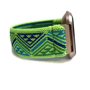 May include: A green, blue and white patterned elastic watch strap with a rose gold watch face.