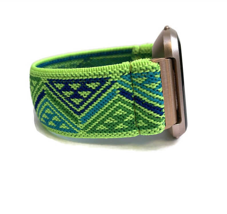 May include: A green, blue and white patterned elastic watch strap with a rose gold watch face.