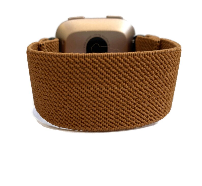 May include: A brown elastic watch band with a gold-colored watch face.