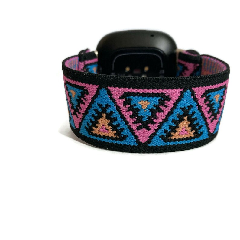 May include: A black watch band with a geometric pattern in pink, blue, and orange. The pattern features repeating triangles.
