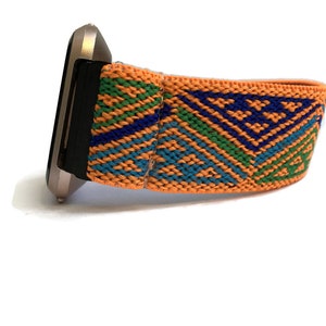 Peut inclure: Gros plan d'une montre avec un bracelet argent&eacute; et un bracelet color&eacute; &agrave; motifs orange, bleu et vert.