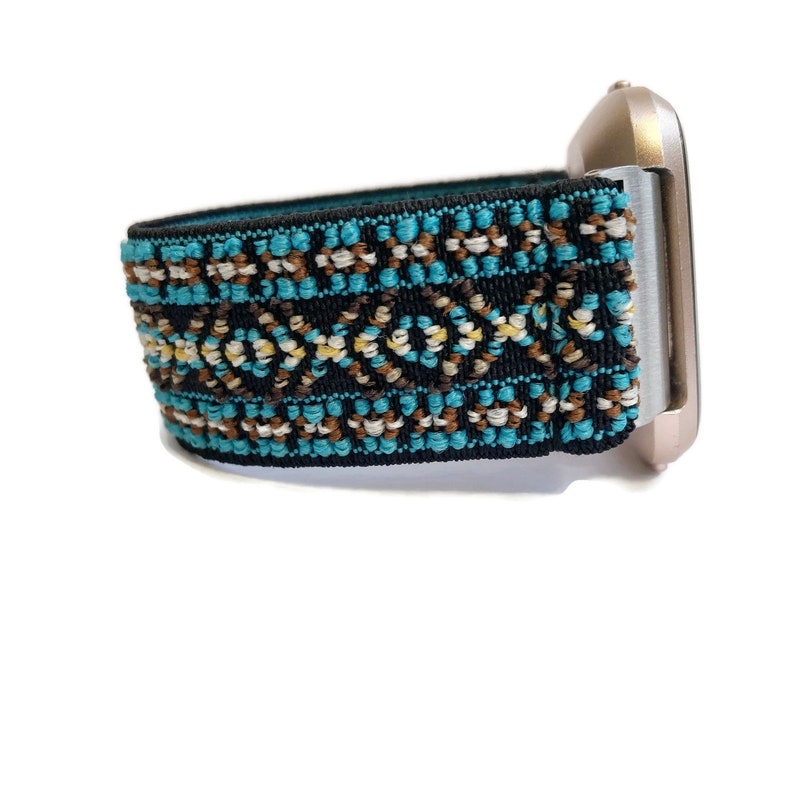May include: A black and turquoise patterned elastic watch band with a gold watch face.