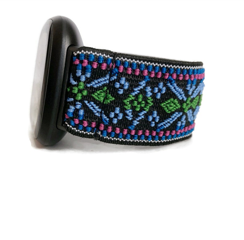 May include: A black watch band with a colourful geometric pattern in shades of blue, green, and pink.