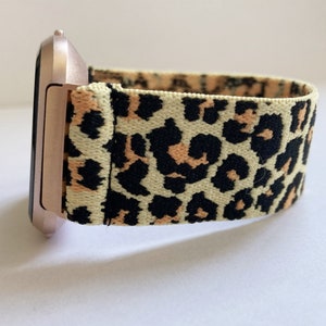 May include: A rose gold smartwatch with a leopard print elastic band.