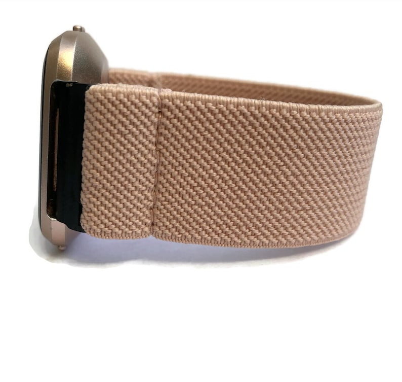 K&ouml;nnte beinhalten: Eine ros&eacute;goldene Smartwatch mit einem hellrosa elastischen Armband.