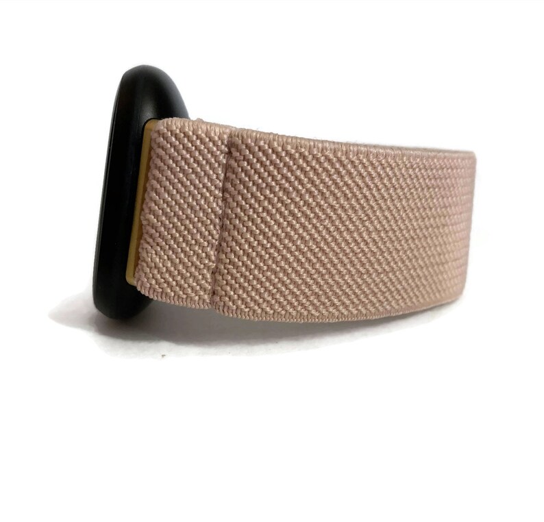 May include: A light pink elastic watch strap with a black metal buckle.