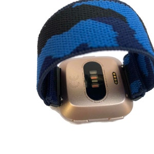 Op de afbeelding: Een smartwatch van ros&eacute;goud met een blauw en zwart camouflageband. Het horloge gezicht toont de tijd en datum.