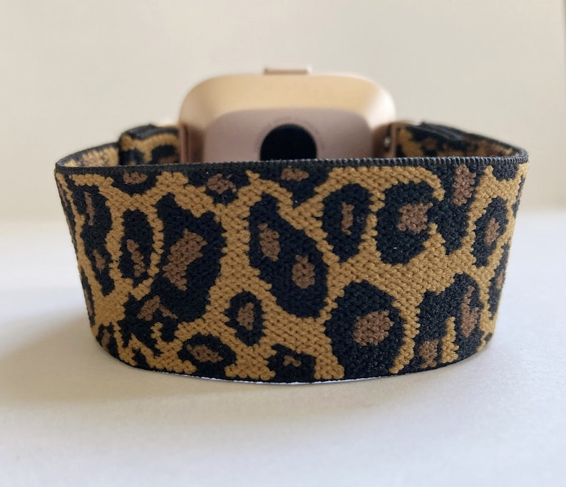 May include: A gold-colored fitness tracker with a leopard print elastic band.