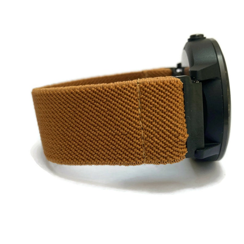 May include: A brown fabric watch band with a black watch face.