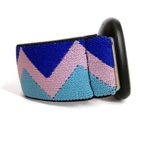 May include: A black watch with a blue, pink and light blue chevron patterned strap.