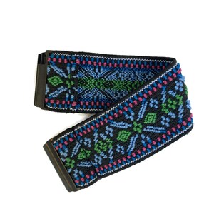 May include: A black elastic belt with a colorful geometric pattern in shades of blue, green, and pink. The belt has a metal buckle.