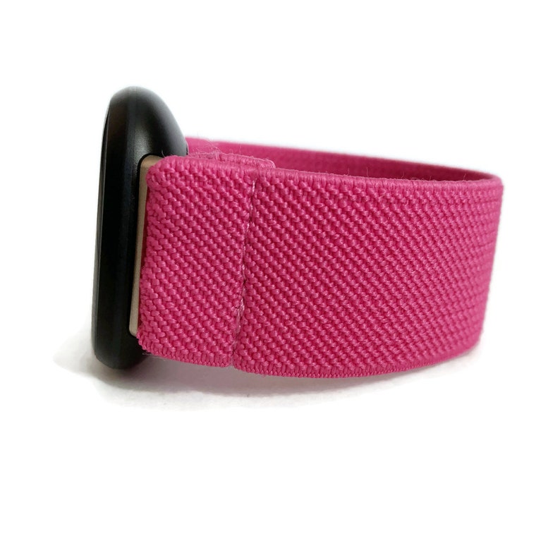 May include: A pink elastic watch band with a black metal buckle.