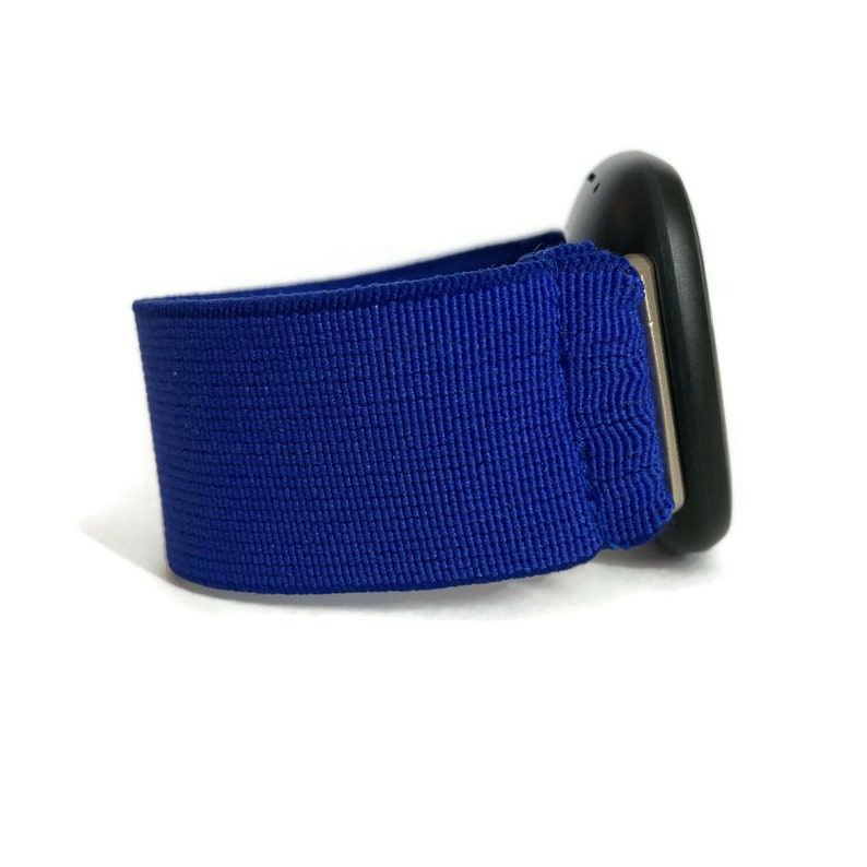 May include: A blue elastic band with a black device attached to it. The device has a rounded shape and a silver trim.