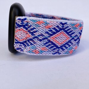 May include: A white, blue, and pink patterned woven watch band with a black watch face.