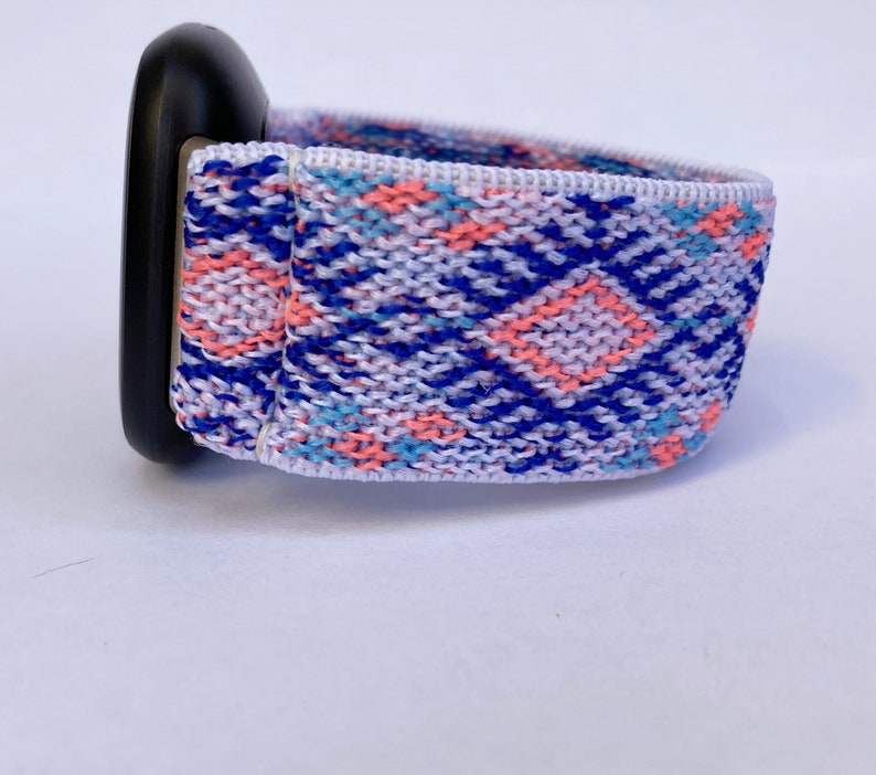 May include: A white, blue, and pink patterned woven watch band with a black watch face.