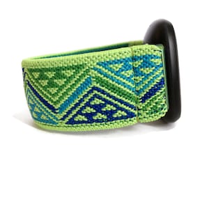 May include: A green, blue, and black patterned elastic watch band with a black watch face.