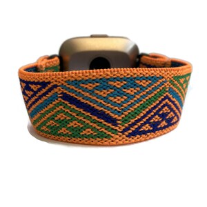 Peut inclure: Bracelet de montre &eacute;lastique orange, vert, bleu et bleu marine. Le bracelet est en tissu tiss&eacute; et pr&eacute;sente un motif g&eacute;om&eacute;trique.